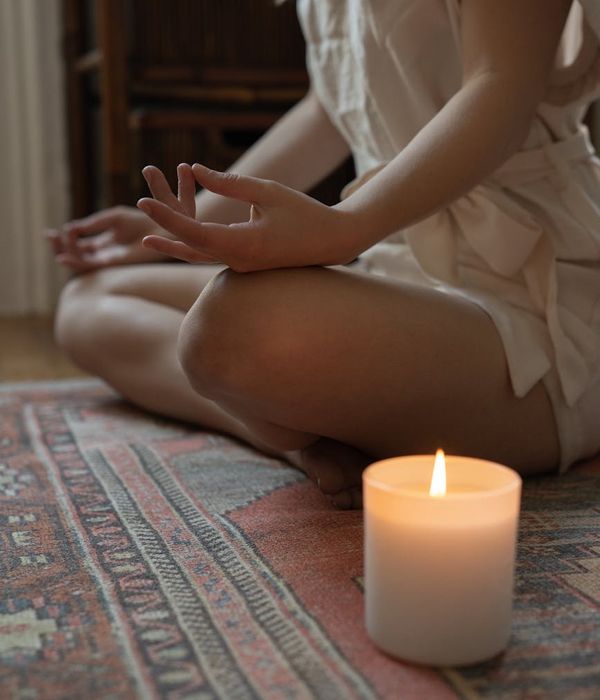 Woman in a calm yoga pose, surrounded by soft purple light.